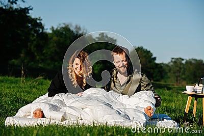 Smiling groggy couple waking up from a nap in bed made outside in a countryside Stock Photo