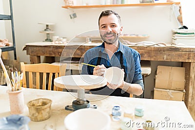 Artist Painting Earthenware With Paintbrush In Pottery Workshop Stock Photo