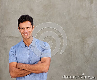 Smiling handsome man standing by wall with arms crossed Stock Photo