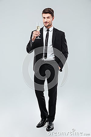 Smiling handsome young businessman standing and holding glass of champagne Stock Photo