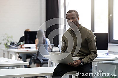 Smiling happy afro american businessman sitting on his desk Stock Photo