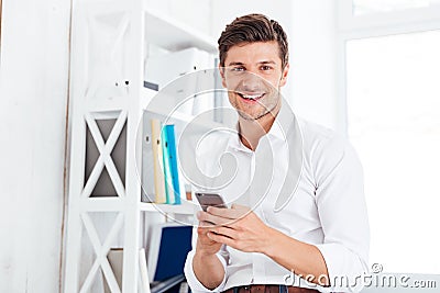 Smiling happy businessman sitting on the table and using smartphone Stock Photo