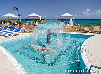 Smiling happy litle girl enjoying swimming and relaxing in water pool with natural sea water Stock Photo