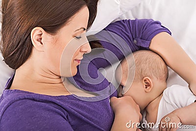 Smiling happy mother breastfeeding her baby infant Stock Photo