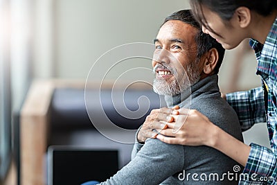 Smiling happy older asian father with stylish short beard touching daughter`s hand on shoulder looking Stock Photo