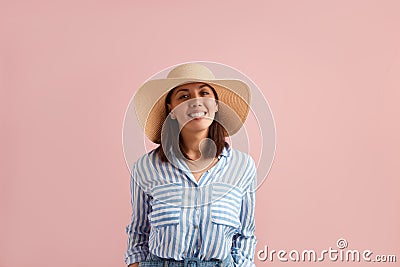 Smiling happy positive woman with dark hair is going on vacation, ready to pack bags, tries on straw hat in a shop Stock Photo