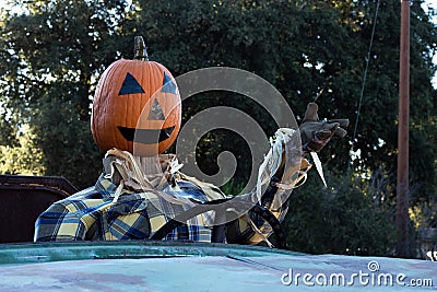 Smiling, happy, welcoming, fun friendly pumpkin head scarecrow driving an old truck to a halloween harvest party Stock Photo