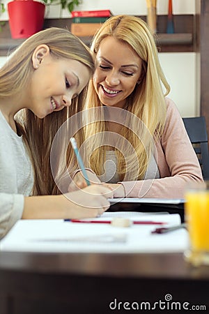 Young woman helping her teenage daughter with homework and studying during pandemic lock-down Stock Photo