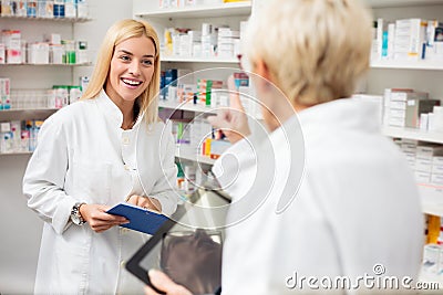 Smiling happy young and mature female pharmacists working behind the counter in a pharmacy Stock Photo