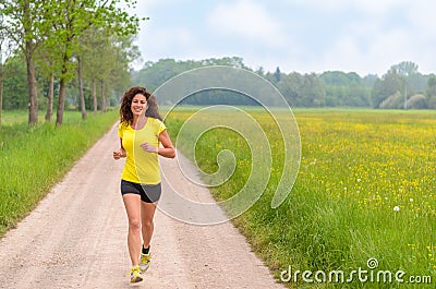 Smiling healthy young woman jogging in nature Stock Photo