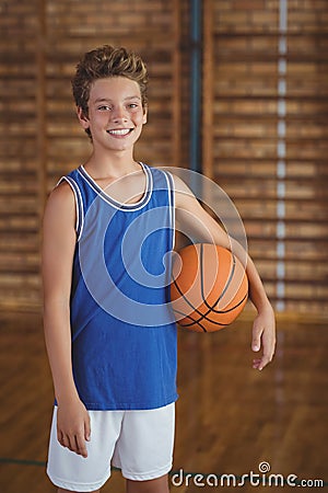 Smiling high school boy holding a basketball in the court Stock Photo