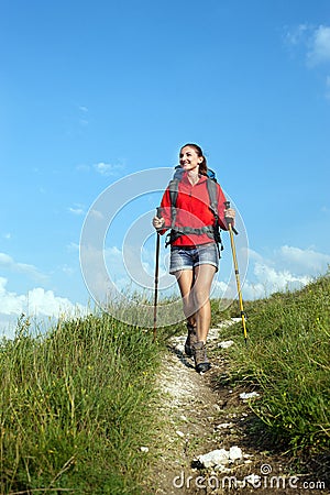 Smiling hiking young woman with backpack and trekking poles Stock Photo