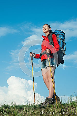 Smiling hiking young woman standing on a green meadow Stock Photo