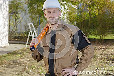 Smiling home inspector holding level at construction site Stock Photo