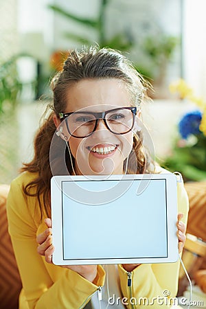 Smiling housewife with headphones showing tablet PC Stock Photo