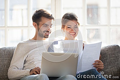 Smiling couple hold paperwork paying bills online Stock Photo