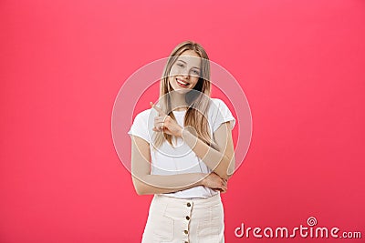 Smiling joyful woman with blonde dyed hair posing against pink studio pointing at copy space for advertisment or Stock Photo