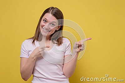 Smiling joyful woman pointing at copy space for advertisment or promotional text Stock Photo
