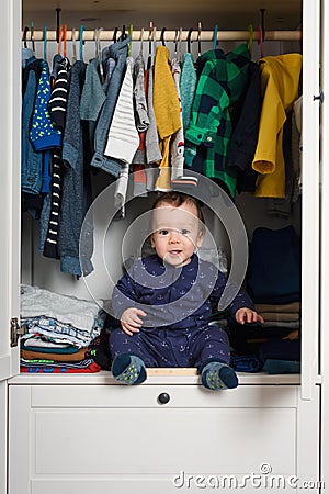 Smiling kid hiden in clothing closet Stock Photo