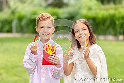 Smiling kids eating fresh vegetables in nature â€“ happy children holding colorful peppers sliced in form of french fries Stock Photo