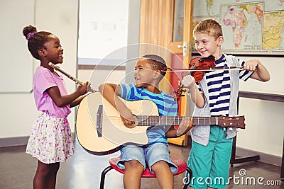 Smiling kids playing guitar, violin, flute in classroom Stock Photo