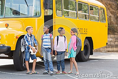 Smiling kids standing together in front of school bus Stock Photo