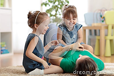 Smiling kids and mom having a fun pastime on floor in children room at home Stock Photo