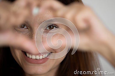 Smiling kind young caucasian attractive woman showing heart. Stock Photo