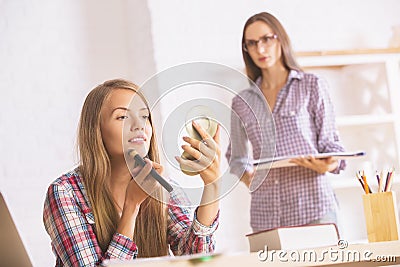 Smiling ladies applying makeup Stock Photo