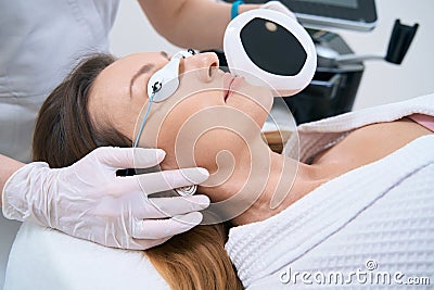 Smiling lady in a medicalcenter undergoing a photorejuvenation procedure Stock Photo