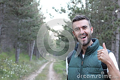 A smiling and laughing brunette holding a thumbs up in approval while standing in the middle of a forest hike. The great outdoors Stock Photo