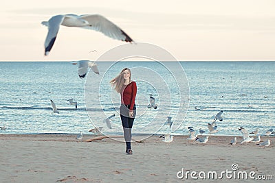 Smiling laughing excited Caucasian young woman in jeans running jumping among seagulls birds Stock Photo