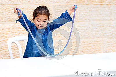 Laughing toddler girl playing with blue slime. Stock Photo
