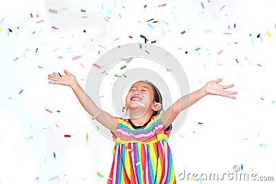 Smiling little Asian kid girl with many falling colorful tiny confetti pieces on white background. Happy New Year or Stock Photo