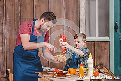 Smiling little boy with father cooking hot dog at backyard Stock Photo