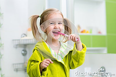 Smiling little girl brushing teeth in bathroom Stock Photo