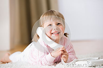 Smiling little girl on carpet with phone Stock Photo