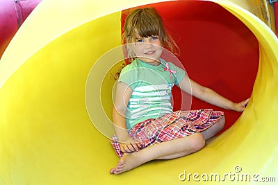 Smiling little girl inside yellow plastic tube Stock Photo
