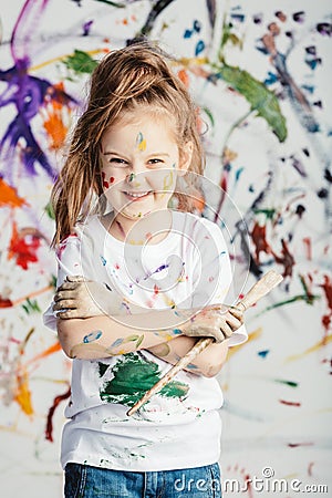 Smiling little girl with painting brush on messy background. Stock Photo