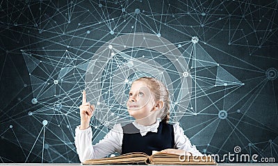 Smiling little girl sitting at desk with open book Stock Photo