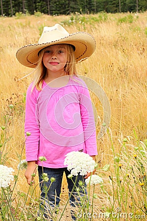 Smiling little girl wearing straw western hat. Stock Photo