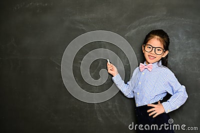Smiling little teacher standing in blackboard Stock Photo