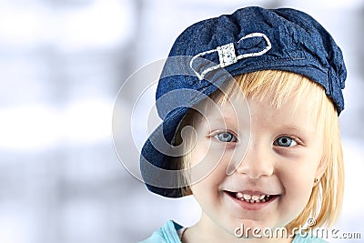 Smiling llittle girl with a cap on her head on a blue background Stock Photo