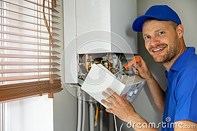 Smiling maintenance and repair service engineer working with house gas heating boiler Stock Photo