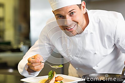 Smiling male chef garnishing food in kitchen Stock Photo