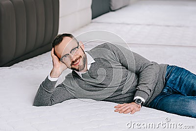 smiling male customer in eyeglasses lying on mattress Stock Photo