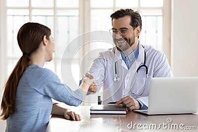 Smiling male doctor handshake female patient in hospital Stock Photo