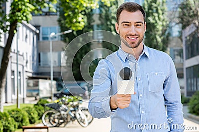 smiling male news reporter taking interview with microphone Stock Photo