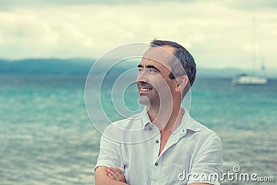 Smiling man with crossed arms by the sea, toothy smile middle ag Stock Photo