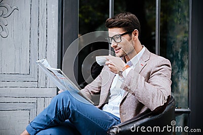 Smiling man drinking coffee and reading magazine in outdoor cafe Stock Photo